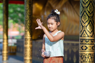 Side view of young woman standing by fence