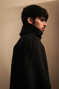 Side view of young man looking away against white background