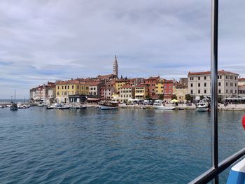 View of buildings by sea against cloudy sky