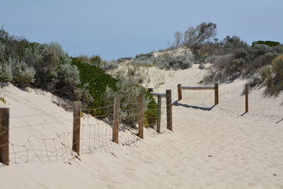 Wooden fence on beach against clear sky