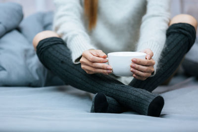 Midsection of woman using mobile phone while lying on bed at home