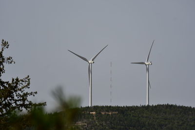 Wind turbines on field against clear sky