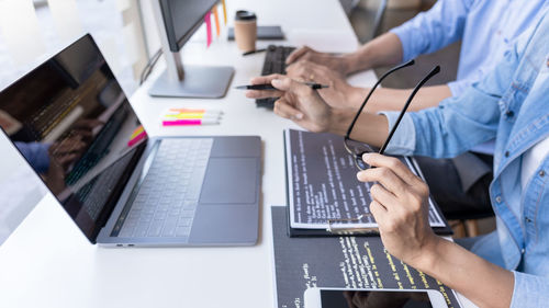 Midsection of computer programmers with laptop working on office desk