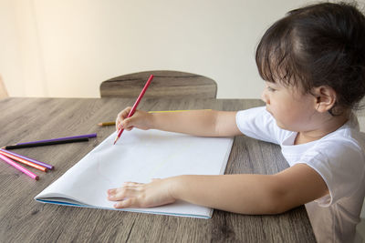 Full length of a boy holding book on table at home