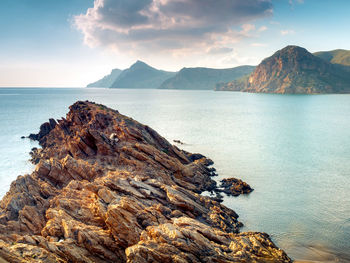 Scenic view of sea and mountains against sky