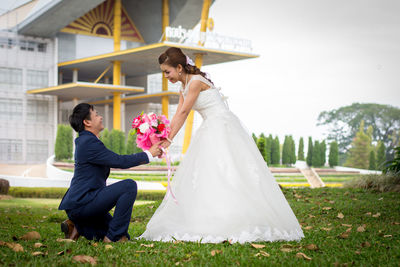 Bridegroom giving bouquet to bride on field