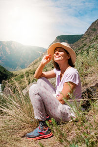 Full length of woman sitting on landscape against mountain range