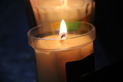 Close-up of burning candle against black background