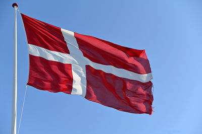 Low angle view of the danish flag against blue sky