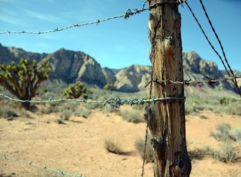 Barbed wire fence on landscape against sky