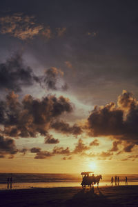 Silhouette people on beach against sky during sunset