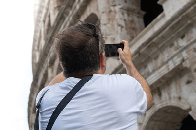 Rear view of man holding camera