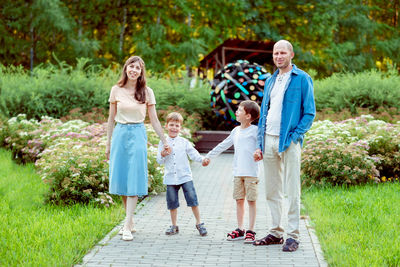 Happy family walks in the park.  mom, dad and 2 sons