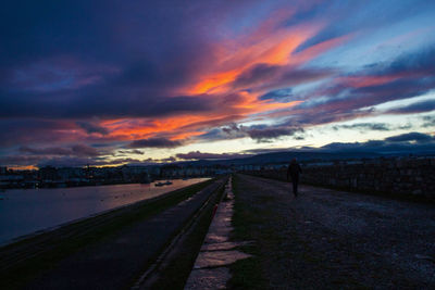 Road amidst dramatic sky during sunset