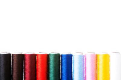 Close-up of multi colored thread spools over white background