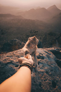 Midsection of woman sitting on rock against mountain