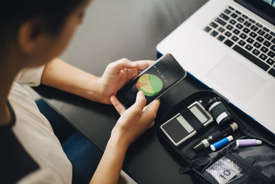 High angle view of businesswoman using mobile phone while doing blood test in office