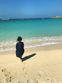 Rear view of woman walking on shore at beach