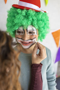 Mother painting her son's face like a clown