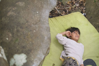 Little boy rests on a crashpad next to a rock