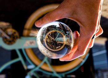 Cropped hand holding crystal ball with bicycle reflection