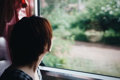 Rear view of woman looking through window