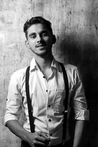 Portrait of young man standing against wall