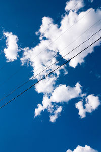 Low angle view of power cables against sky