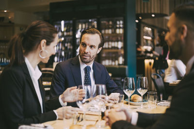 Confident businessman talking to businesswoman in restaurant