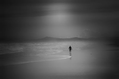 Silhouette people standing on beach against sky