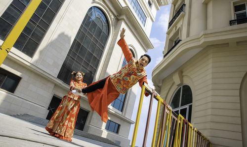 Low angle view of person standing by railing against buildings