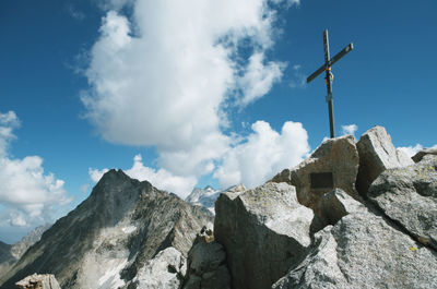 Low angle view of cross on rock against sky