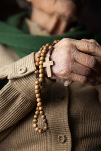 Close-up of woman hand holding cross on wood