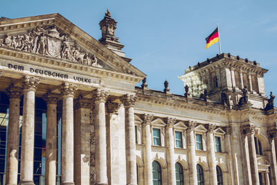 Low angle view of german flag on reichstag building against clear blue sky