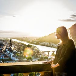 Side view of smiling woman looking at city from balcony 