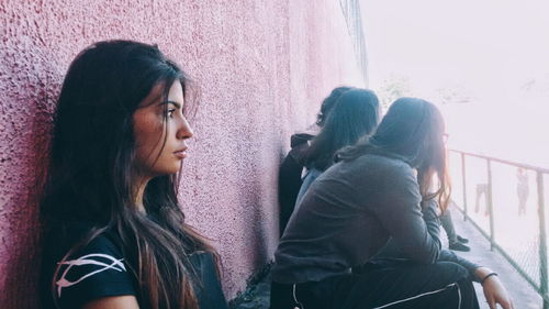 Young woman looking away while sitting on floor