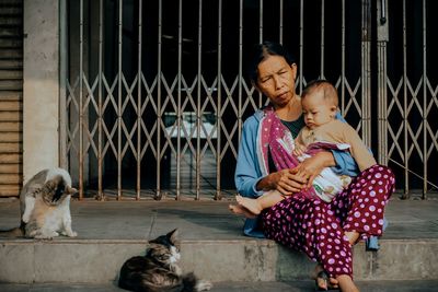 Full length of woman with son sitting outdoors