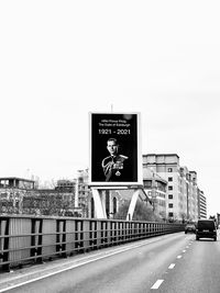 Information sign on road in city against clear sky