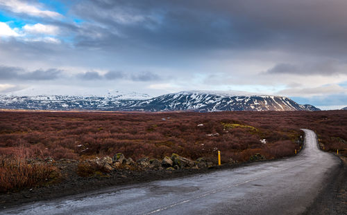 Road by snowcapped mountain against sky