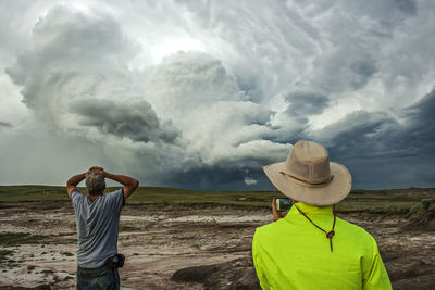 Rear view of people standing on beach against sky