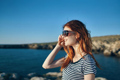 Young woman wearing sunglasses against clear sky