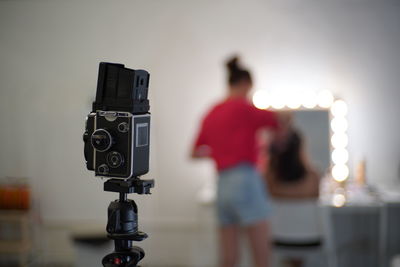 Close-up of camera with woman in background