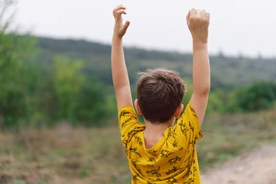 A six-year-old boy is standing with his back in the countryside. back view.