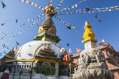 Low angle view of praying flags on temple against clear blue sky