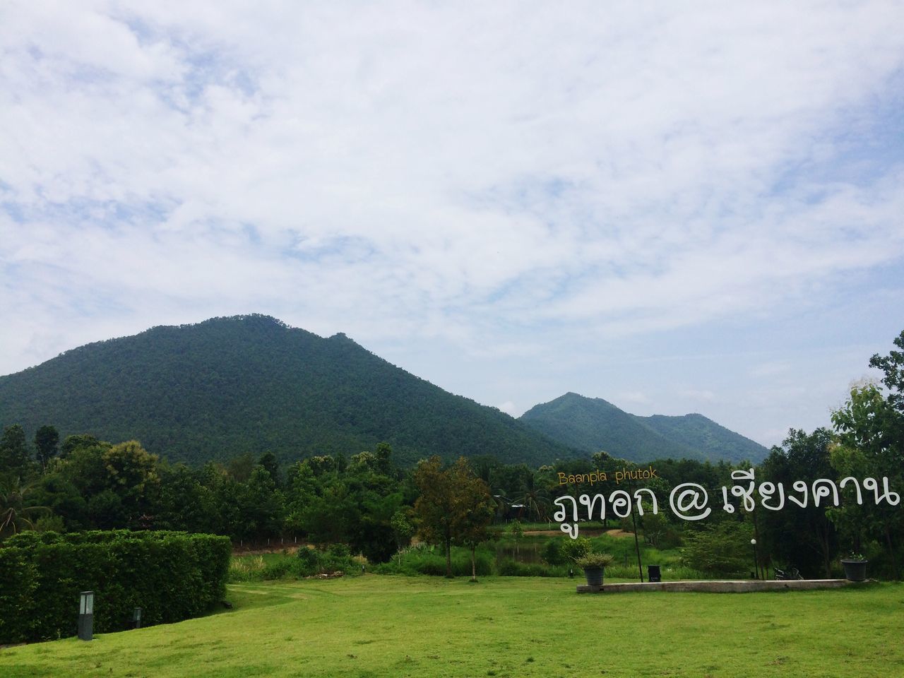 mountain, text, sky, western script, landscape, tranquil scene, communication, mountain range, non-urban scene, scenics, tranquility, cloud, information sign, cloud - sky, field, nature, day, beauty in nature, green color, outdoors, rural scene, remote, solitude, agriculture, tourism, signboard, majestic, vacations