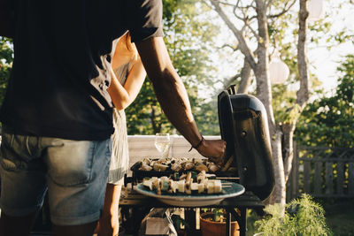 Midsection of man standing on barbecue grill in yard