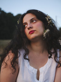 Close-up of thoughtful young woman with flowers on hair