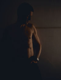 Full length of shirtless man standing against black background