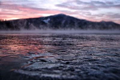 Scenic view of frozen lake and mountain against sky during sunrise