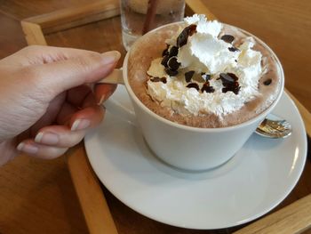 Close-up of hand holding tea cup on table